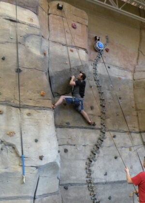 Rock wall photo with a a man belaying another man on the wall