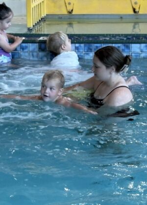 photo of a lifeguard helping a boy float on his stomach in the pool