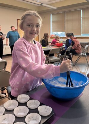 photo of a girl smiling and whisking ingredients in a bowl