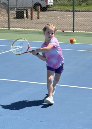 photo of a girl swinging her racket for a tennis ball