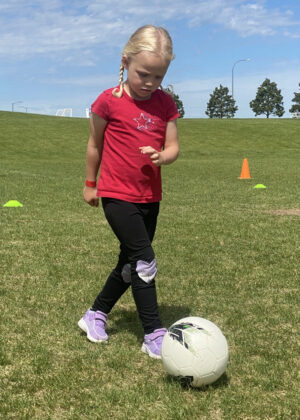 photo of a girl kicking a soccer ball