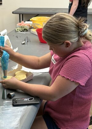 photo of a girl frosting a cupcake with a piping bag