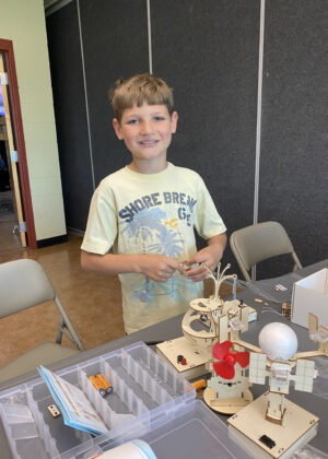 photo of a boy building with wood and tools